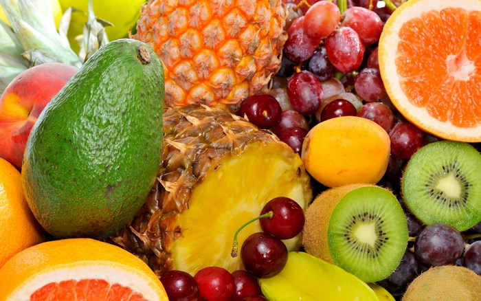A vibrant assortment of fresh fruits including pineapple, avocado, grapes, kiwi, and grapefruit.