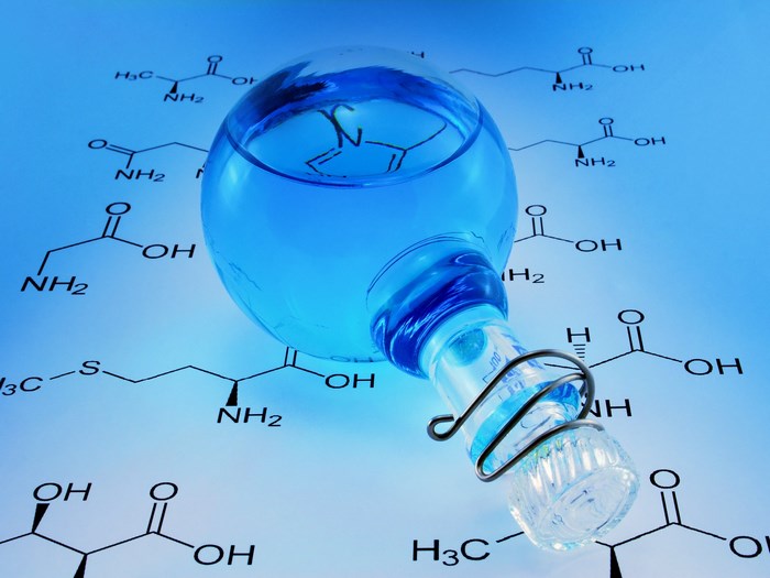 Chemistry flask with blue liquid on chemical formulas