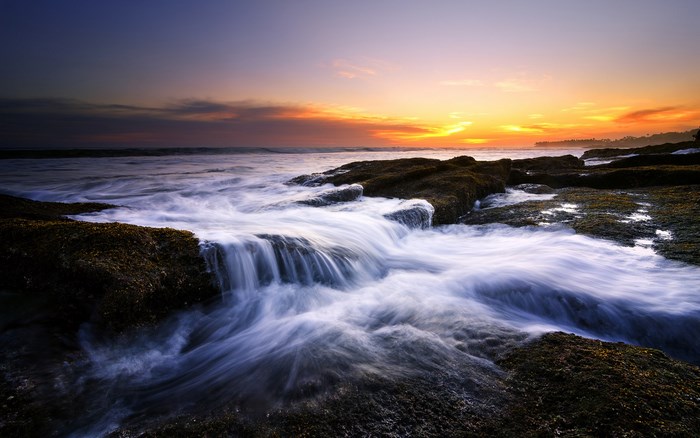 Ocean waves crashing on rocks at sunset