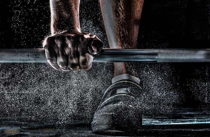 Weightlifter gripping barbell with chalk dust