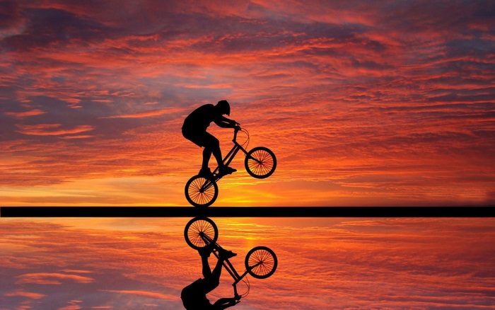 BMX rider performing a stunt at sunset