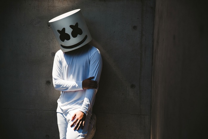 Marshmello leaning against a concrete wall