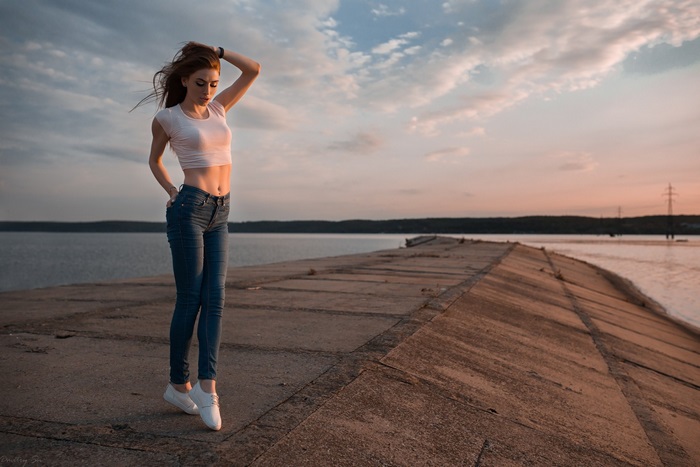 Young Woman Standing on Pier at Sunset