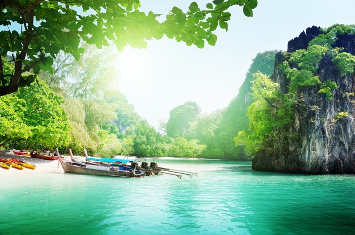 Tropical beach with longtail boats and kayaks