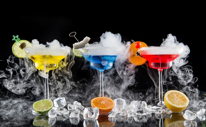 Cocktails with dry ice and fruit garnishes