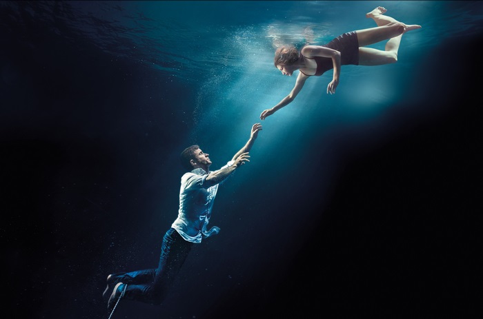 Man and woman reaching for each other underwater
