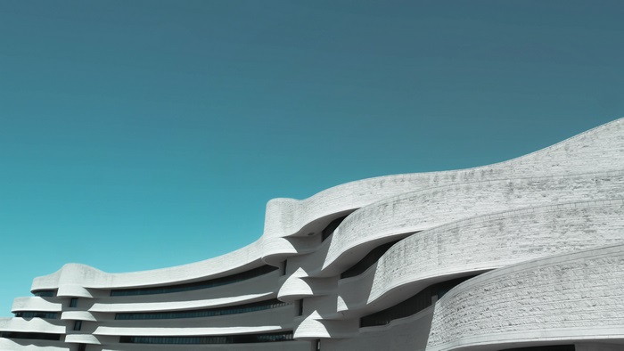 Curving stone building against a clear blue sky