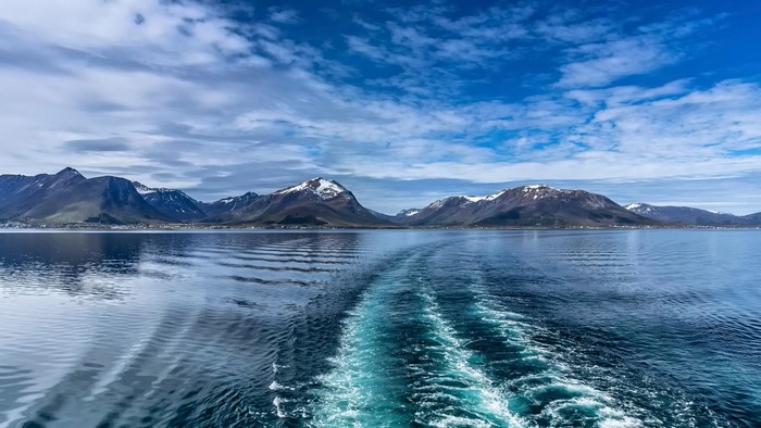Snow-capped mountains and sea with boat wake