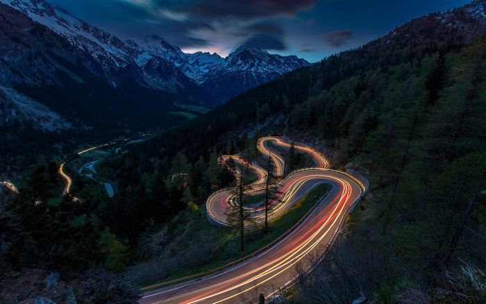 Mountain road with car light trails at dusk