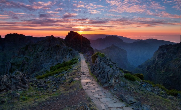 Mountain hiking path at sunset with clouds