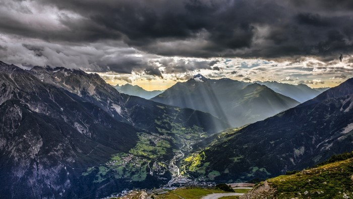 Sunlight Piercing Through Clouds over Austrian Alps Valley