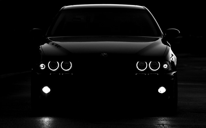 Black BMW car with illuminated headlights