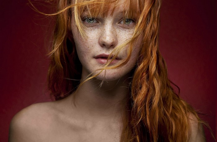 Redhead woman with freckles and hair in face