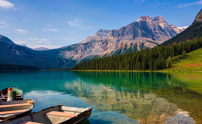 Boats on a clear lake with mountains and forest
