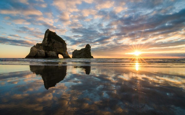 Sunset over ocean with rock formations and reflection