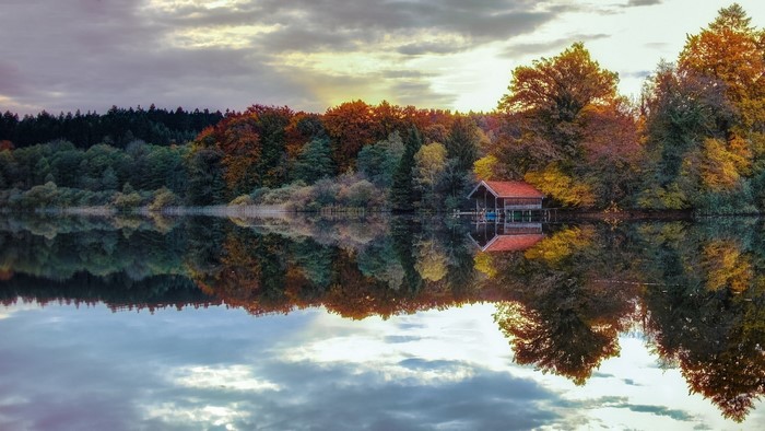 Tranquil Lake Reflection with Autumn Trees and Cabin