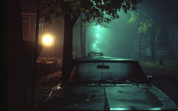 Abandoned car on a foggy street at night