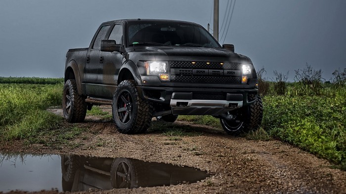 Black Ford Raptor truck on a dirt road