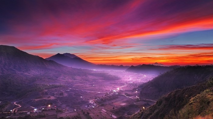 Valley village at sunset with pink clouds and mountains