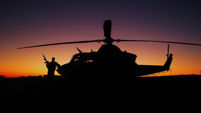 Silhouette of a soldier and helicopter at sunset