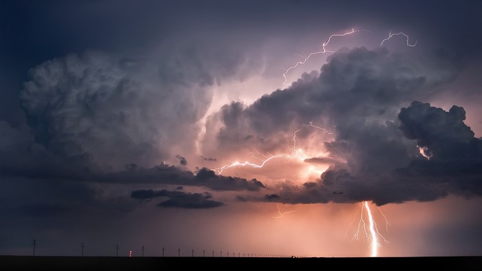 Lightning storm over a flat horizon with power lines
