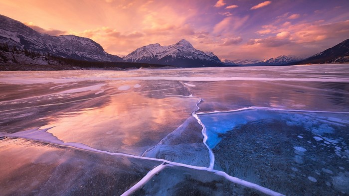 Frozen lake with mountains at sunset
