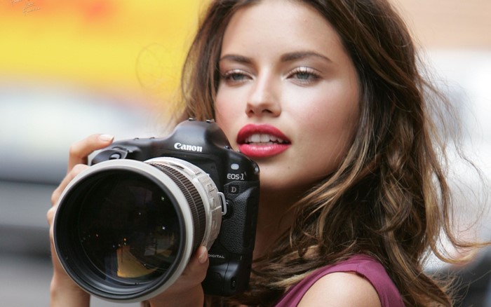 Adriana Lima holding a Canon EOS-1D camera