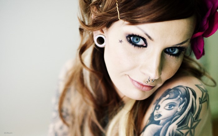 Woman with blue eyes, tattoos, and piercings