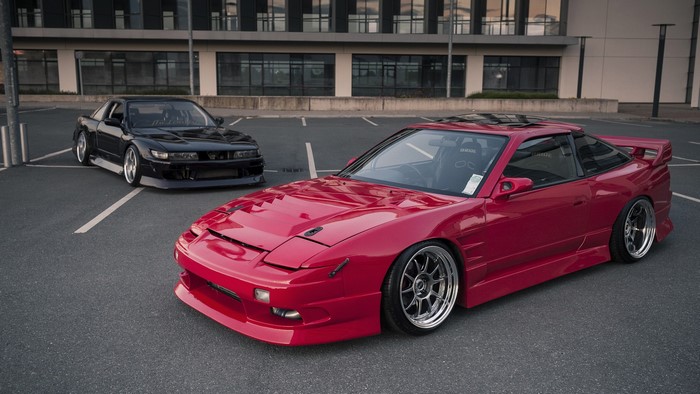 Two Nissan Silvia S13 cars parked in a lot