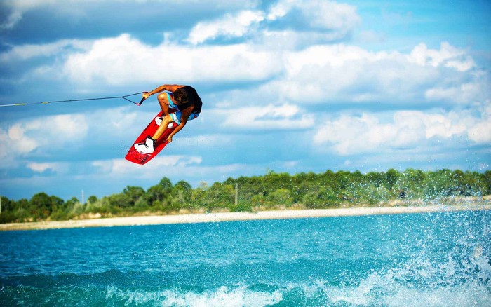 Wakeboarder jumping over water with trees in background