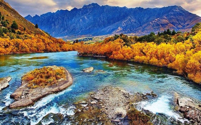 River flowing through autumn forest with mountains