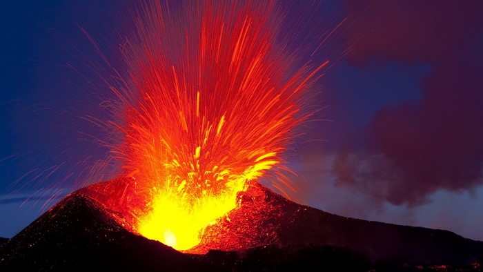 Volcano erupting with lava and ash at dusk