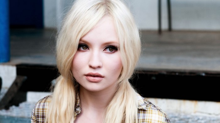 Emily Browning with blonde hair wearing a plaid shirt
