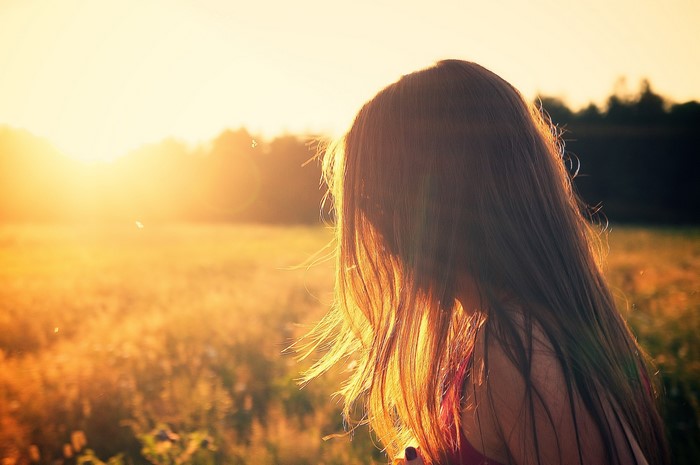 Girl with long hair in a field at sunset