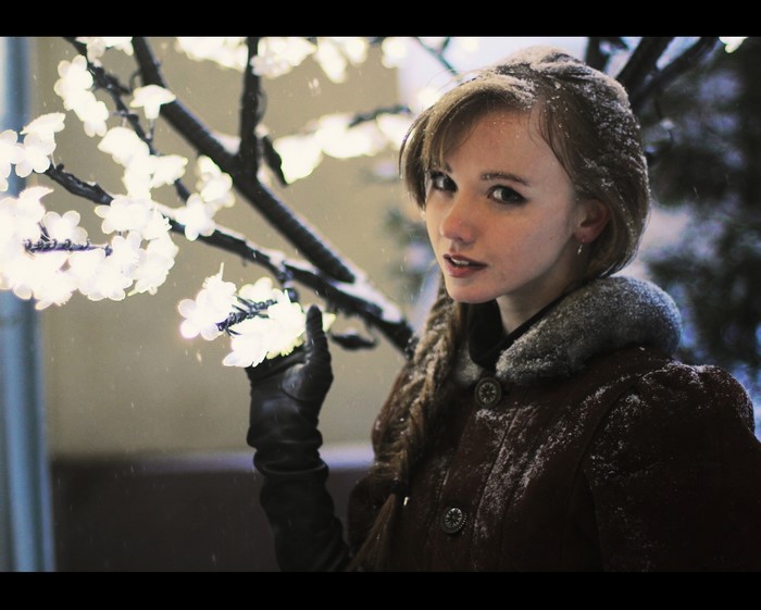 Winter Portrait of Woman with Snow and Lighted Blossoms