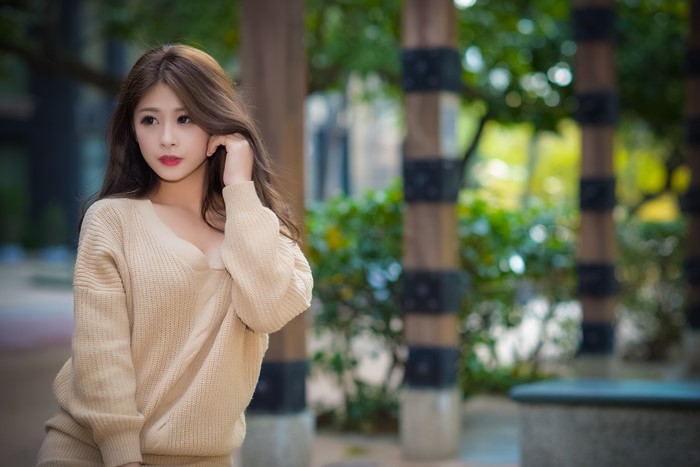 Woman with long auburn hair wearing a sweater outdoors
