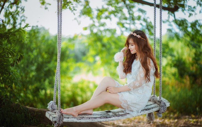 Asian woman with flower crown on a swing