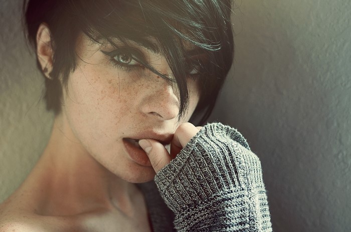 Woman with freckles and finger in mouth