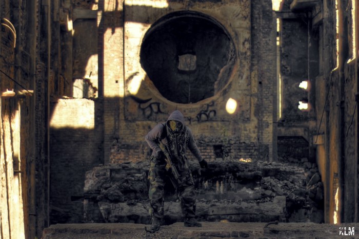 Man in gas mask and camouflage in abandoned building