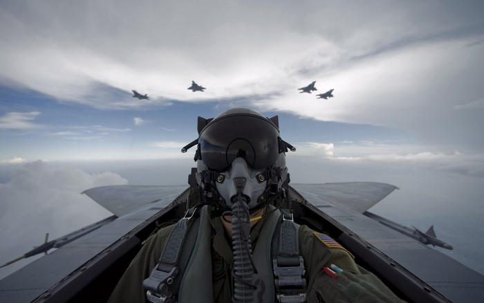 Pilot in fighter jet cockpit with other jets flying