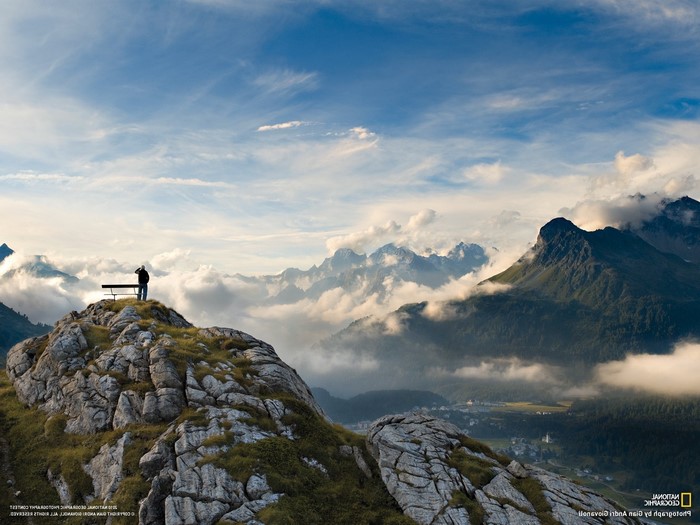 Man on mountain peak overlooking clouds and Italian Alps