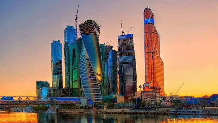 Moscow City skyscrapers at sunset with river and bridge