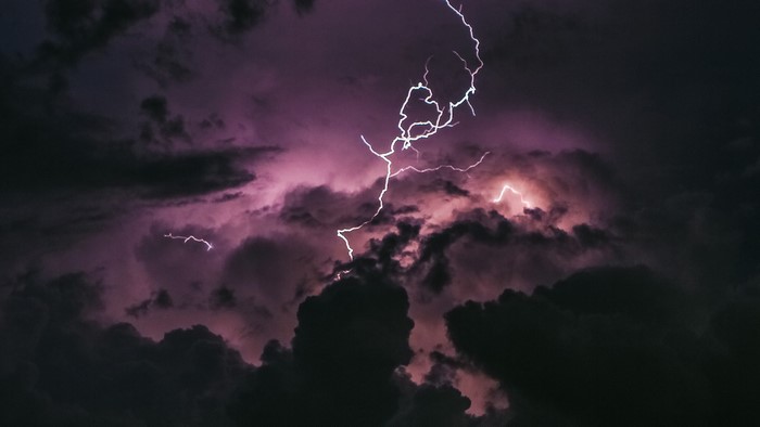 Lightning strikes through dark purple storm clouds