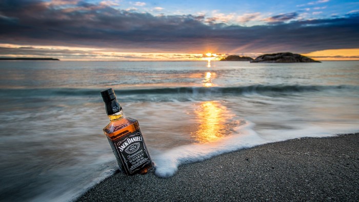 Jack Daniels bottle on a beach at sunrise