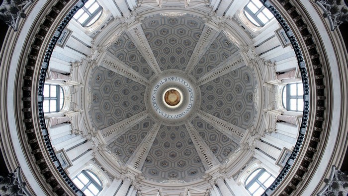Interior of a grand dome with ornate carvings and windows