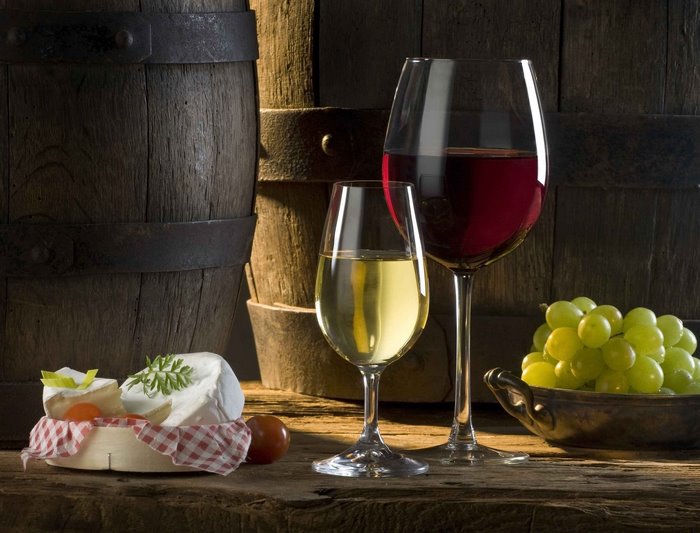 Wine, cheese, and grapes with barrels
