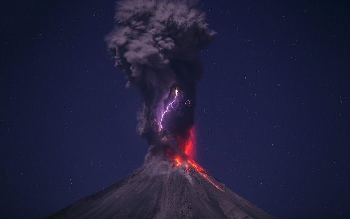 Volcano erupting with lightning at night