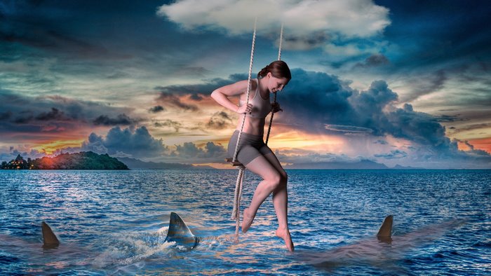 Woman on swing over sea with sharks
