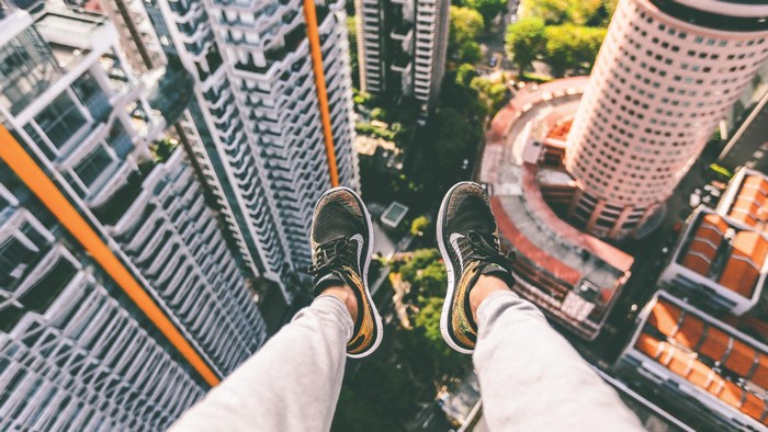 Person sitting on edge of skyscraper