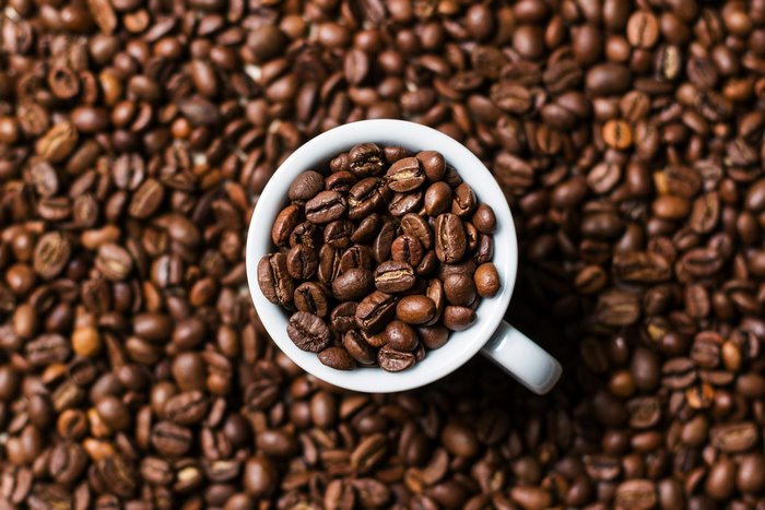 Overhead view of coffee beans in a white cup